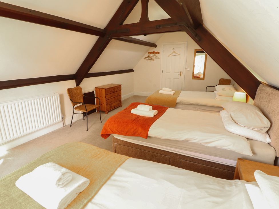 A bedroom with three beds and a chair at Hawkshead Hall in Hawkshead