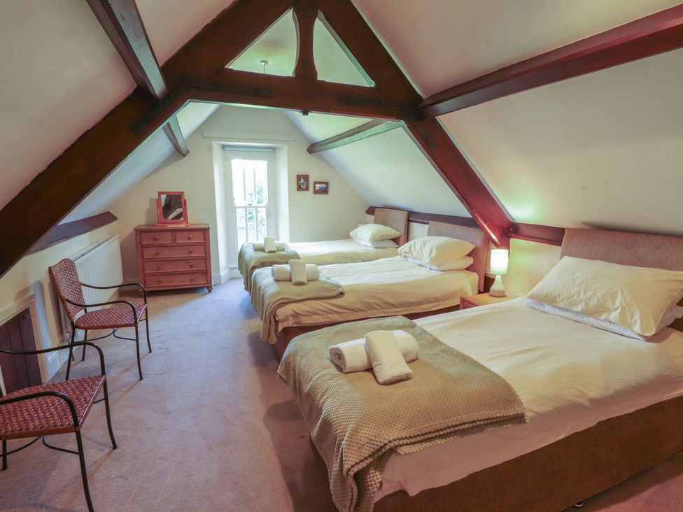 A bedroom with three beds and a dresser at Hawkshead Hall in Hawkshead