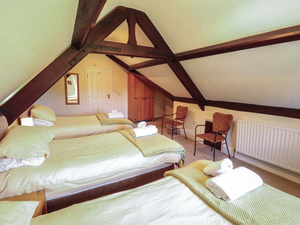 A bedroom with three beds and two chairs at Hawkshead Hall in Hawkshead