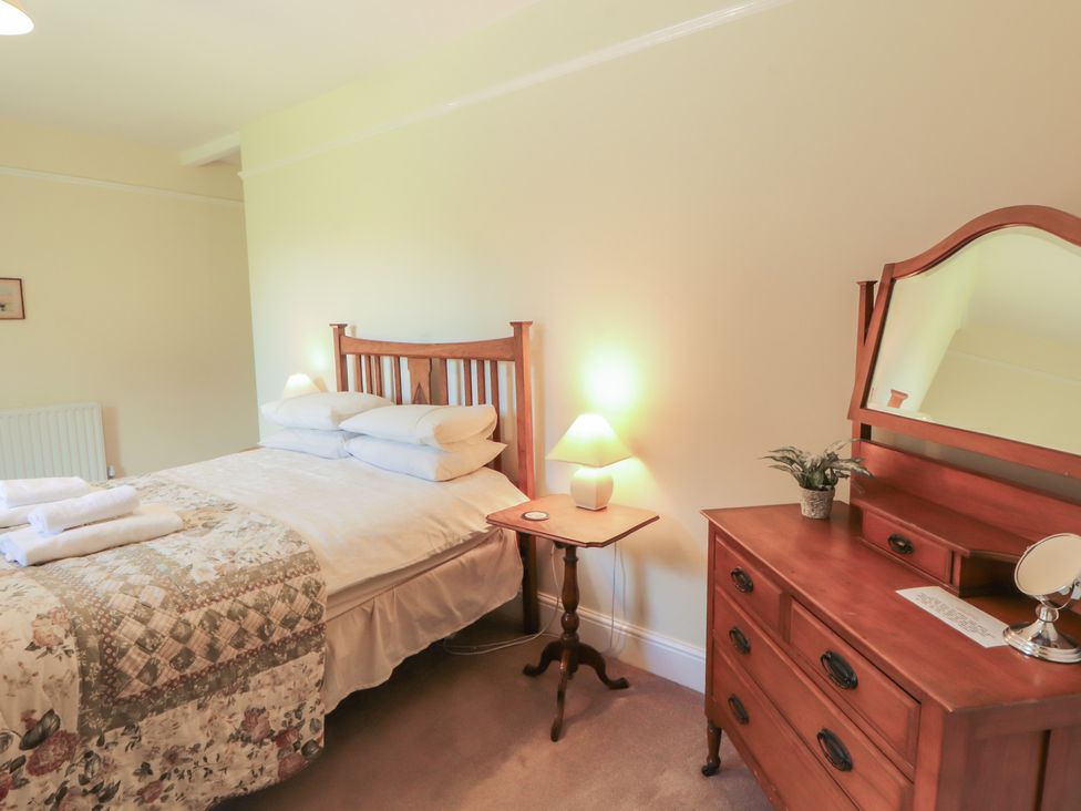 A bedroom with a bed and dresser at Hawkshead Hall in Hawkshead