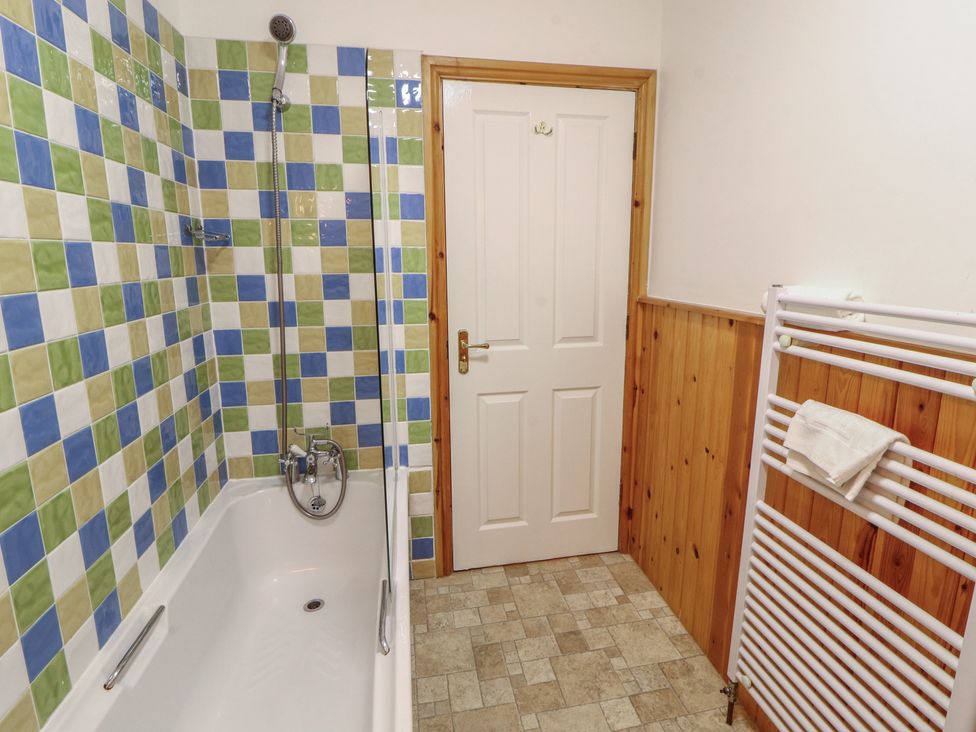 A bathroom with a bathtub and tiled walls at Hawkshead Hall in Hawkshead