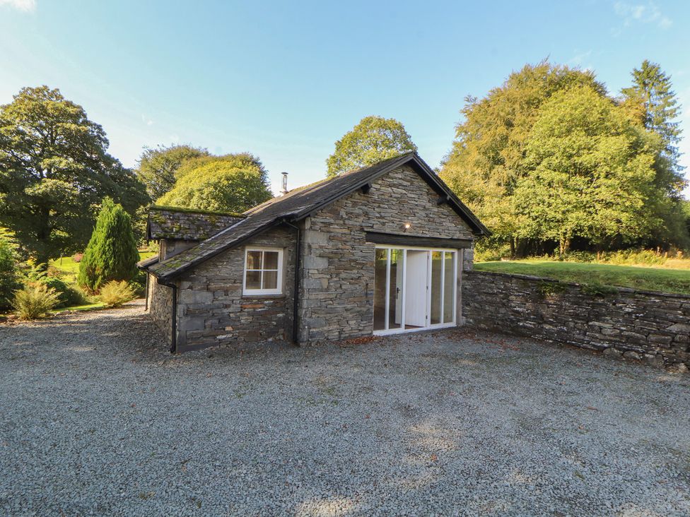 A stone building with windows and a gravel driveway at Hawkshead Hall in Hawkshead