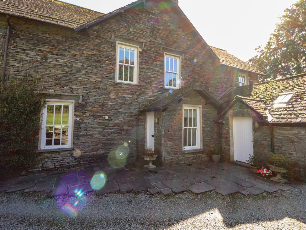 An exterior view of a stone house with a pathway and flowers at Hawkshead Hall in Hawkshead