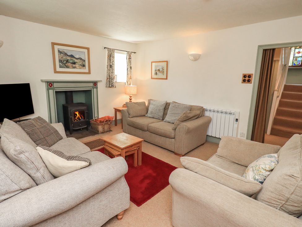 A living room with a fireplace and seating at Rose Cottage Coniston