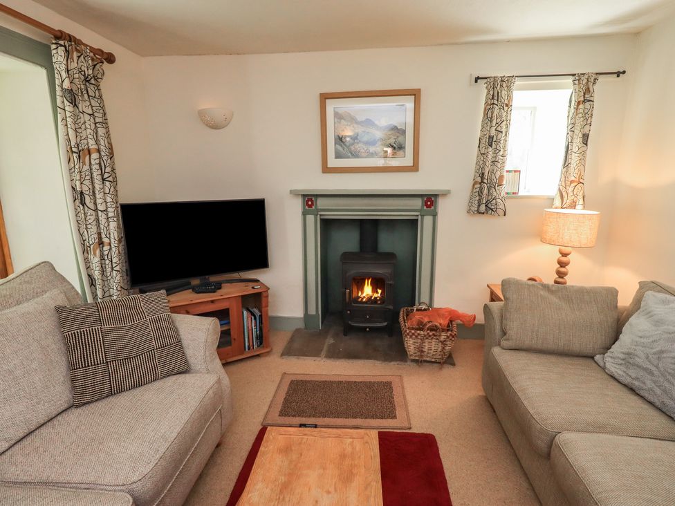 A living room with a fireplace and television at Rose Cottage Coniston