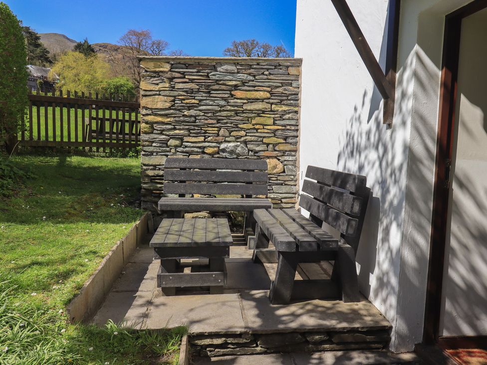 A patio area with wooden benches and a table at Rose Cottage Coniston