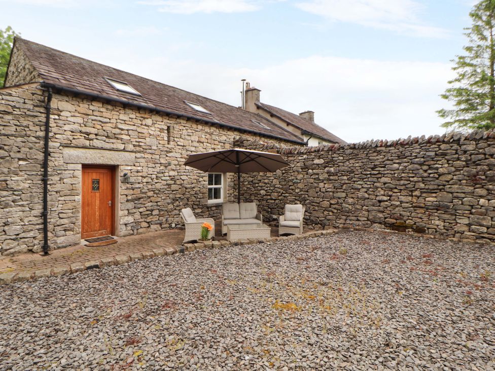 An outdoor space with a stone wall and seating area at Durham Bridge Barn in Crosthwaite