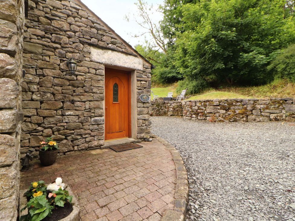 An outdoor entrance with a stone wall and wooden door at Durham Bridge Barn in Crosthwaite