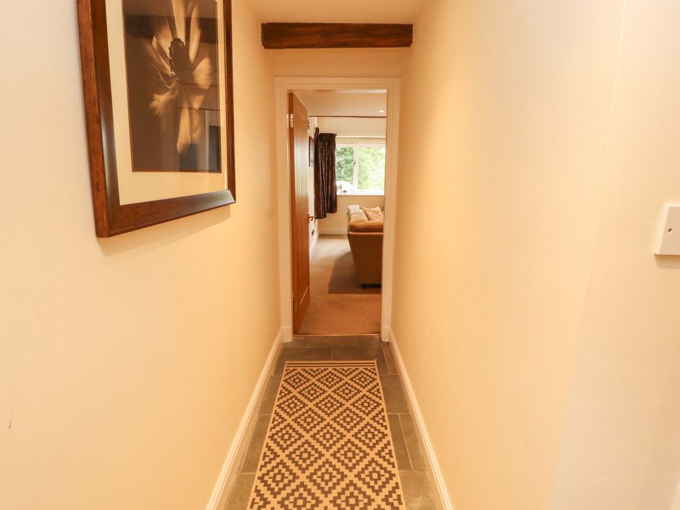A hallway with a framed picture and view of a living room at Durham Bridge Barn in Crosthwaite