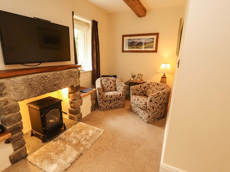 A living room with a television and two armchairs at Durham Bridge Barn in Crosthwaite