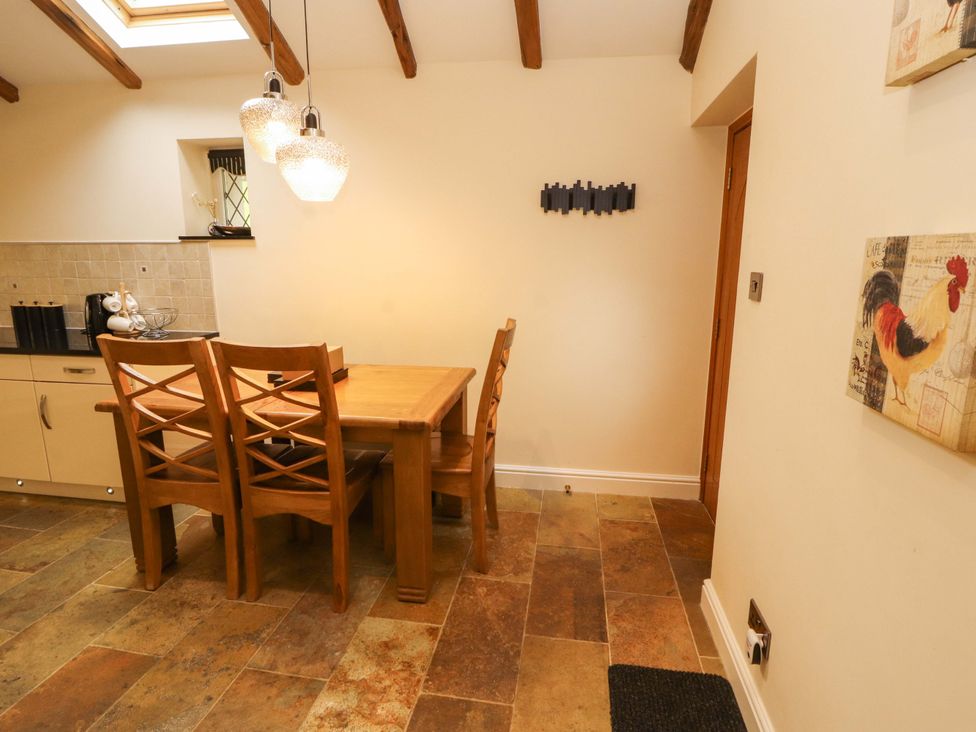 A dining room with a wooden table and chairs at Durham Bridge Barn in Crosthwaite