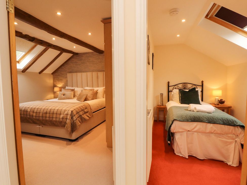 A bedroom featuring two beds and a window at Durham Bridge Barn in Crosthwaite