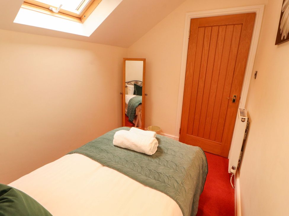 A bedroom with a bed and mirror at Durham Bridge Barn in Crosthwaite