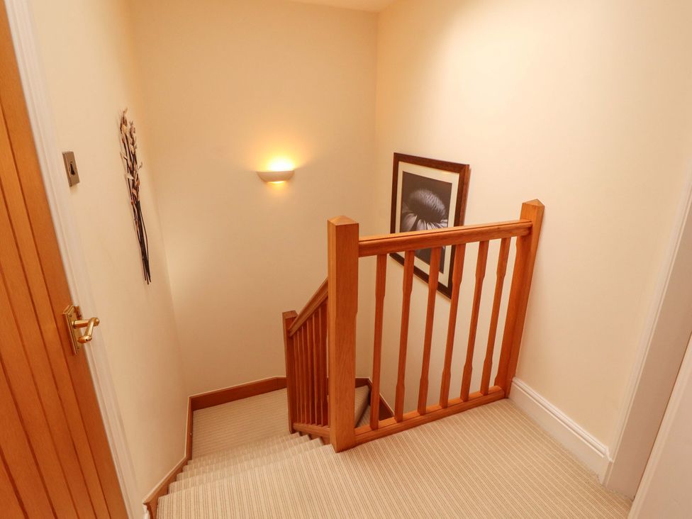 A staircase with a handrail and wall light at Durham Bridge Barn in Crosthwaite