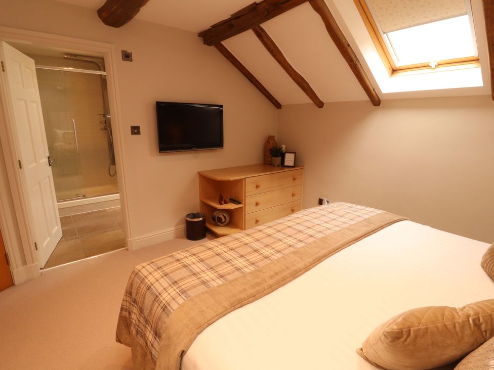 A bedroom with a bed and television at Durham Bridge Barn in Crosthwaite