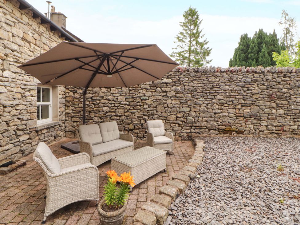 An outdoor seating area with a sofa, chairs, and umbrella at Durham Bridge Barn Crosthwaite