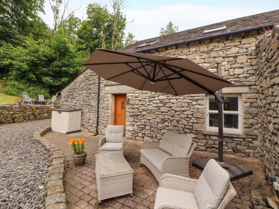 An outdoor seating area with furniture and a stone wall at Durham Bridge Barn in Crosthwaite