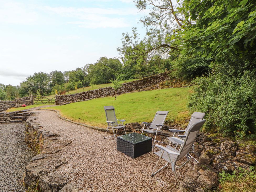 A garden area with chairs and a table at Durham Bridge Barn in Crosthwaite