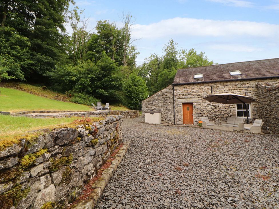 An outdoor area with stone walls and seating at Durham Bridge Barn in Crosthwaite