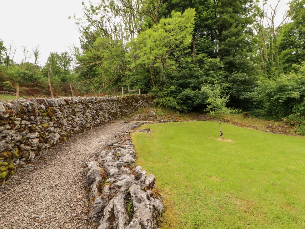 A garden with a stone wall and gravel path at Durham Bridge Barn in Crosthwaite
