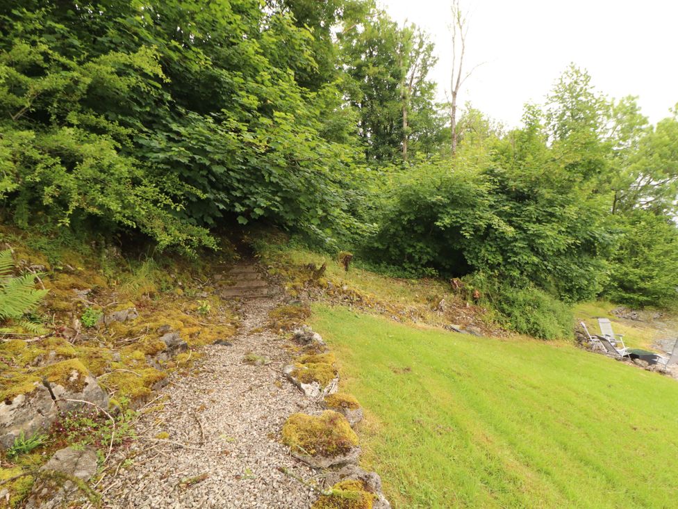 A garden path leading through bushes and trees at Durham Bridge Barn Crosthwaite