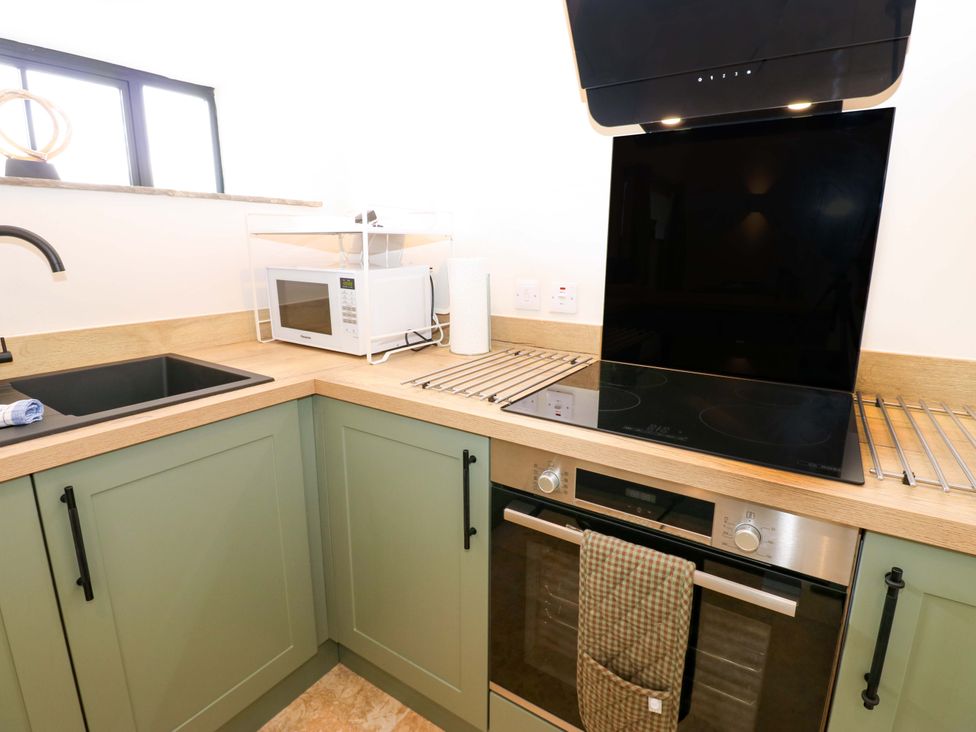 A kitchen with a sink, microwave, and oven at Hadrian Barn 1 in Ebchester
