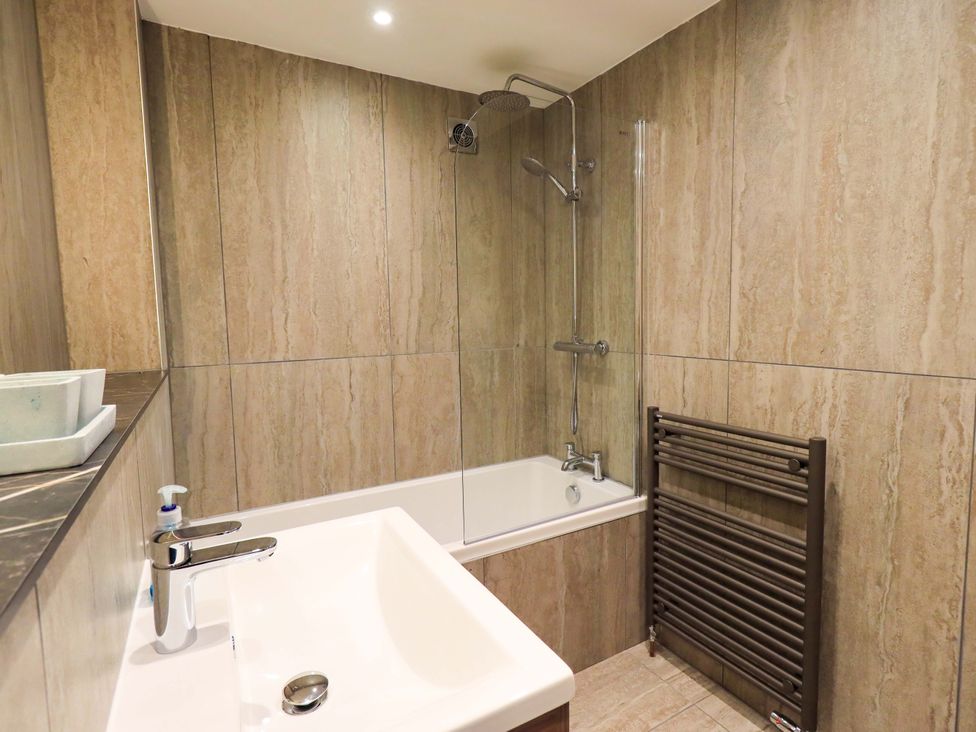 A bathroom with shower over a bath and sink at Gillybeck in Ambleside