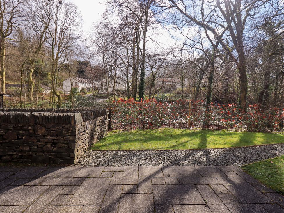 A garden with a stone wall and flowers at Gillybeck in Ambleside