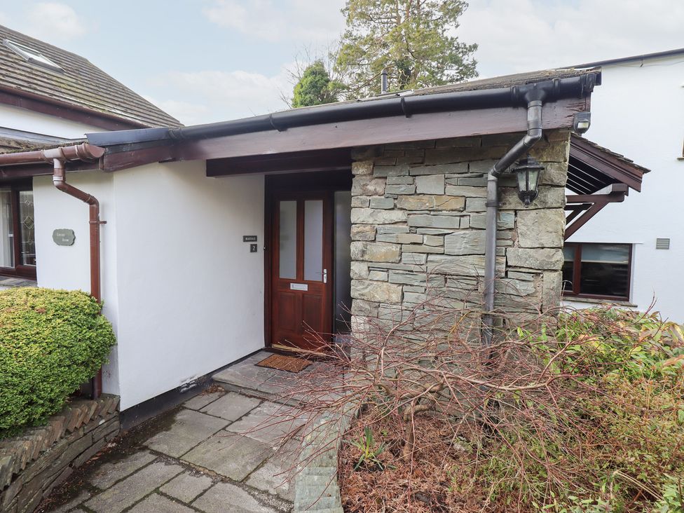 An entrance with a stone wall and wooden door at Mardale in Ambleside
