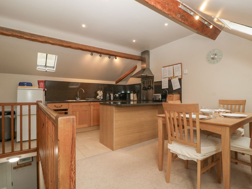 A kitchen with an island, dining table and chairs at Cygnet Cottage Thornthwaite