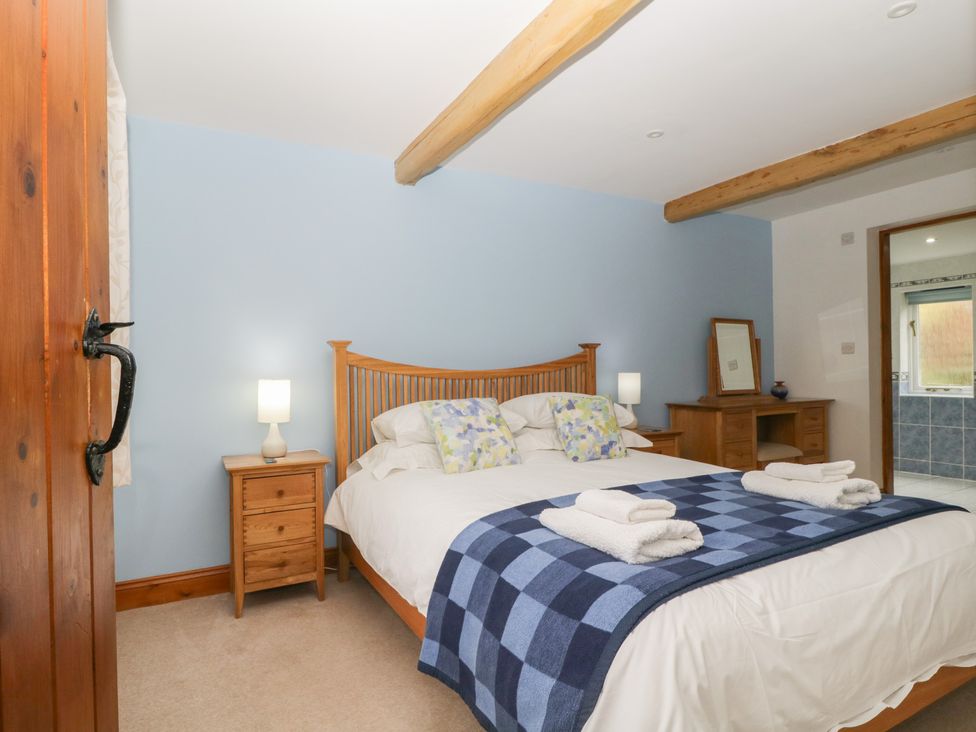 A bedroom with a bed and bedside lamp at Cygnet Cottage Thornthwaite