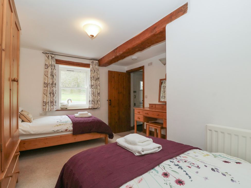 A bedroom with two beds and a dresser at Cygnet Cottage Thornthwaite