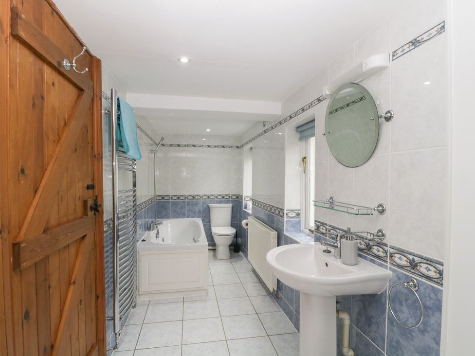 A bathroom with a bathtub, sink and toilet at Cygnet Cottage Thornthwaite