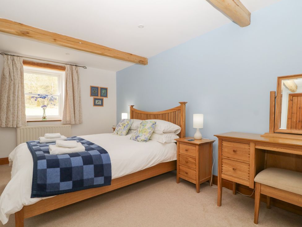 A bedroom with a bed and desk at Cygnet Cottage Thornthwaite