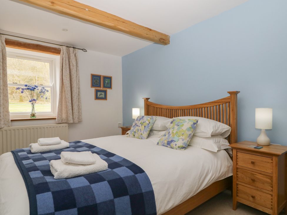 A bedroom with a bed and bedside tables at Cygnet Cottage Thornthwaite