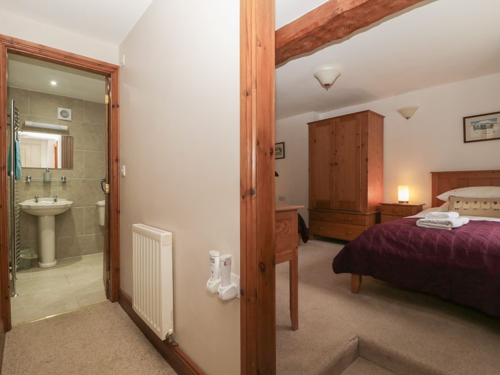 A bedroom with a bed and wardrobe at Cygnet Cottage Thornthwaite