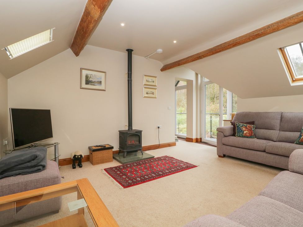 A living room with a television and wood stove at Cygnet Cottage in Thornthwaite