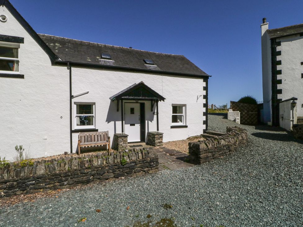 A house with a bench and stone wall at Cygnet Cottage in Thornthwaite