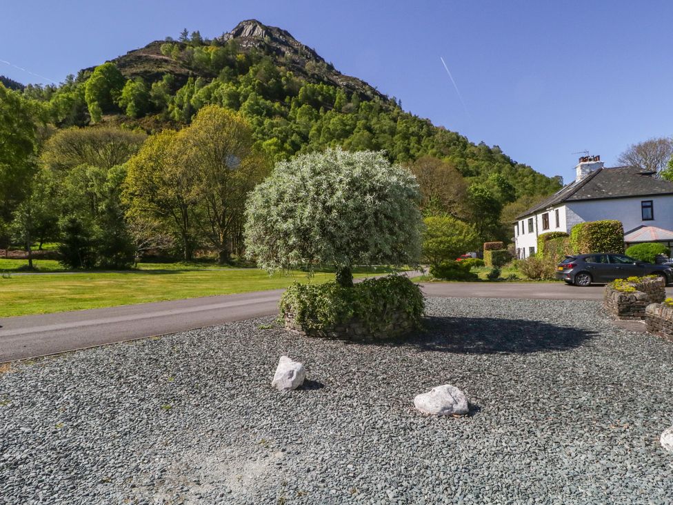 A view of a house with a tree and gravel in front at Cygnet Cottage in Thornthwaite