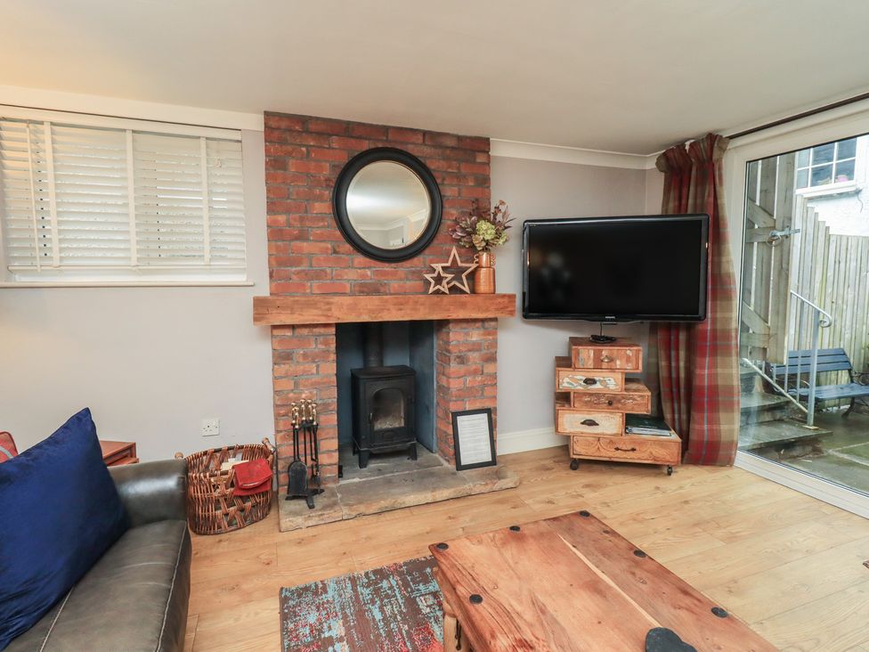 A living room with a fireplace and television at Chapel Hill Cottage in Ambleside