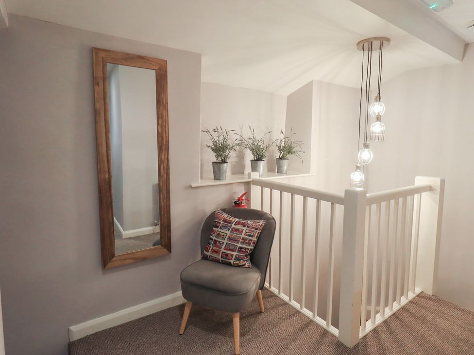 A hallway with a mirror and chair at Chapel Hill Cottage in Ambleside