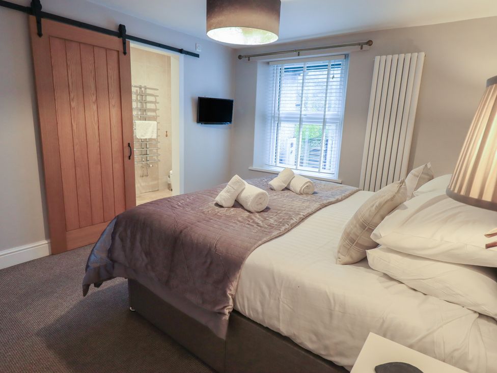 A bedroom with a bed and towels at Chapel Hill Cottage in Ambleside