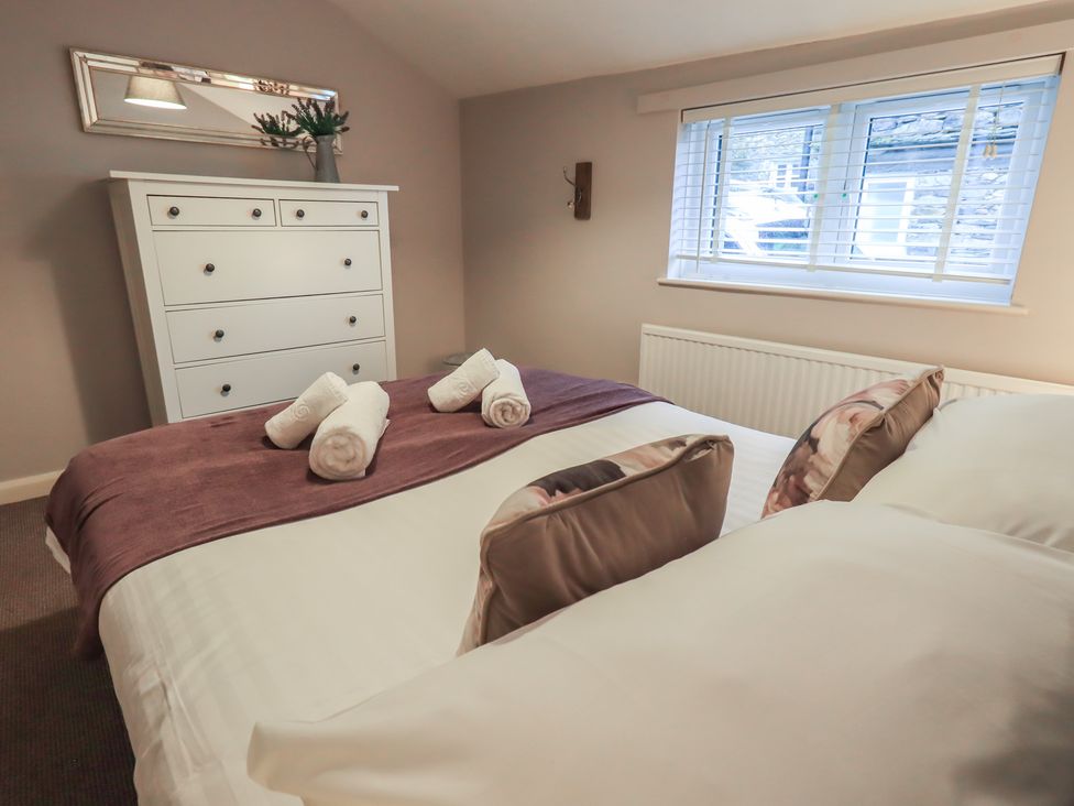 A bedroom with a bed and dresser at Chapel Hill Cottage, Ambleside