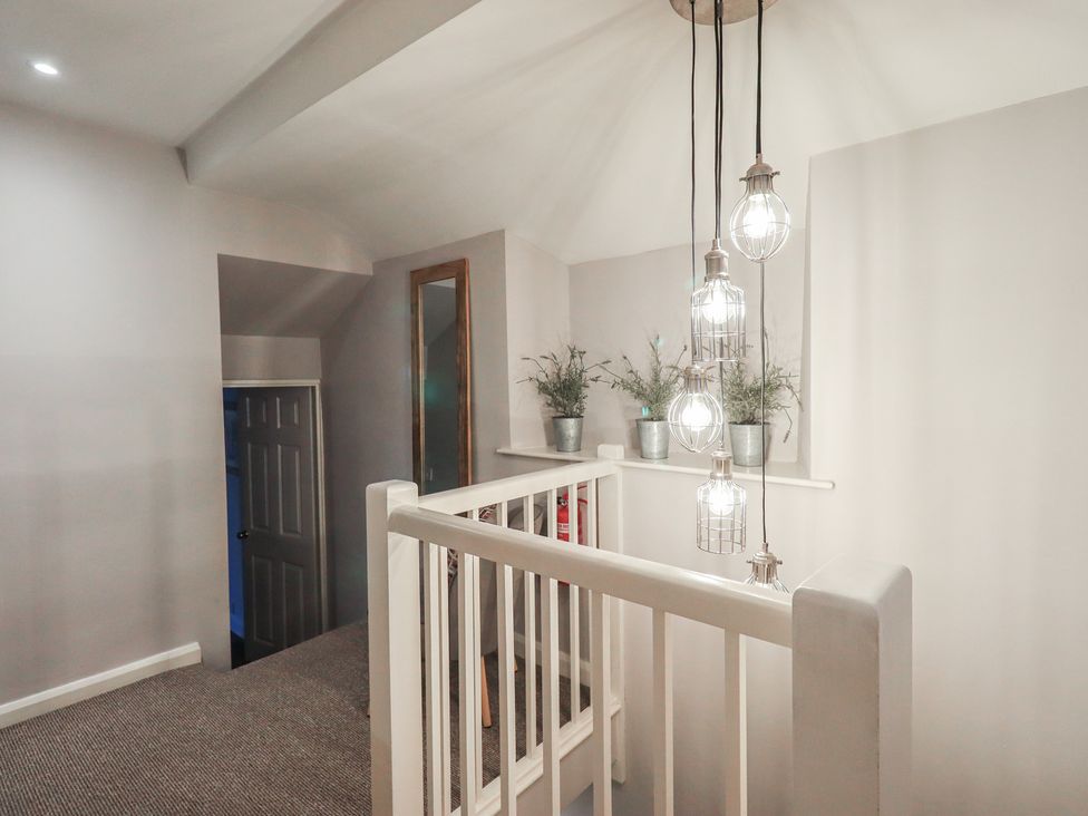 A hallway with a staircase and light fixtures at Chapel Hill Cottage in Ambleside