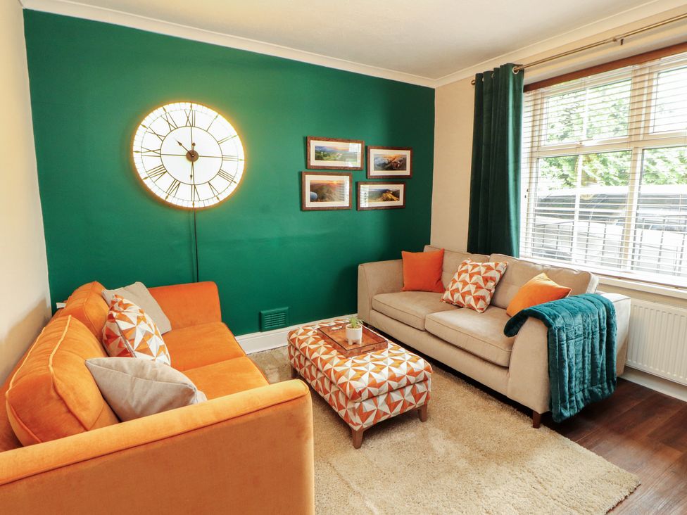 A living room with a clock and sofa at Gildabrook Cottage in Bowness