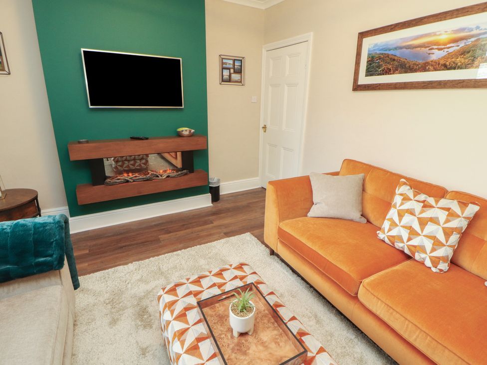 A living room with a television and a sofa at Gildabrook Cottage in Bowness