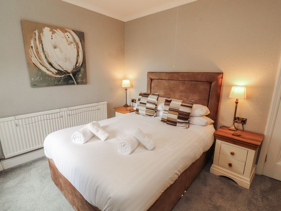 A bedroom with a bed and bedside table at Gildabrook Cottage Bowness