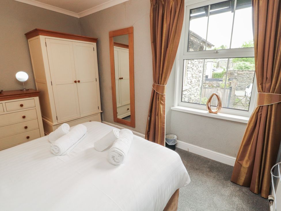A bedroom with a bed and wardrobe at Gildabrook Cottage in Bowness