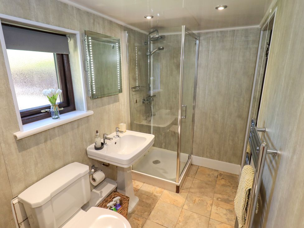 A bathroom with a toilet sink shower and towel rack at The Cottage in Keswick