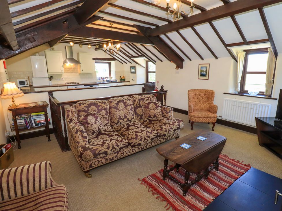 A living room with patterned sofas a wooden coffee table and a kitchen counter at The Cottage in Keswick